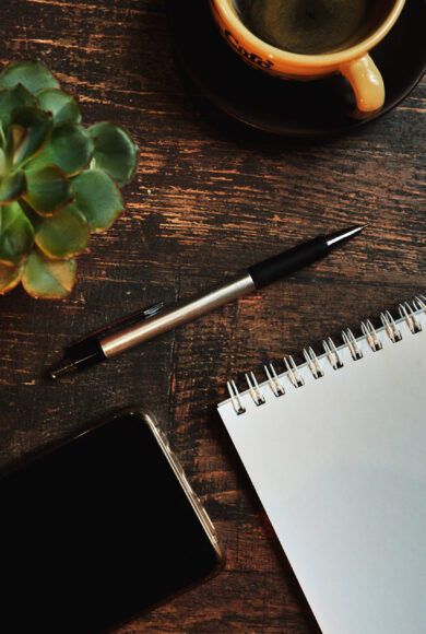 Workplace with a coffee Cup, on a wooden table An empty paper note with a pen. The Concept Of A Business Plan. Workplace with a coffee Cup, phone on a wooden table