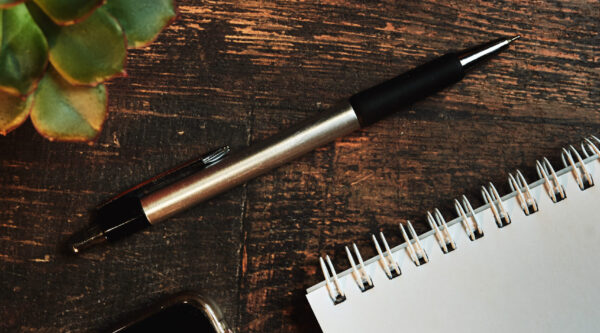 An empty paper note with a pen. The Concept Of A Business Plan. Workplace with a coffee Cup, phone on a wooden table