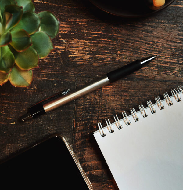 An empty paper note with a pen. The Concept Of A Business Plan. Workplace with a coffee Cup, phone on a wooden table
